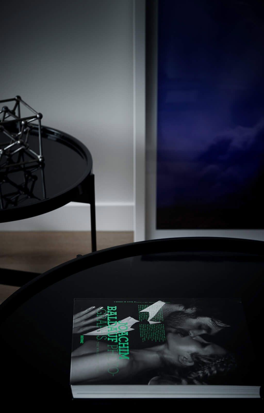 Side table with magazine. Dark blue painting in background.