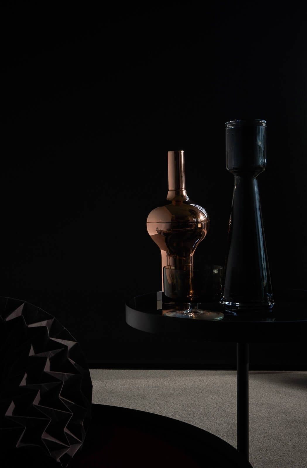 reflective vases in front of black wall in dark tones