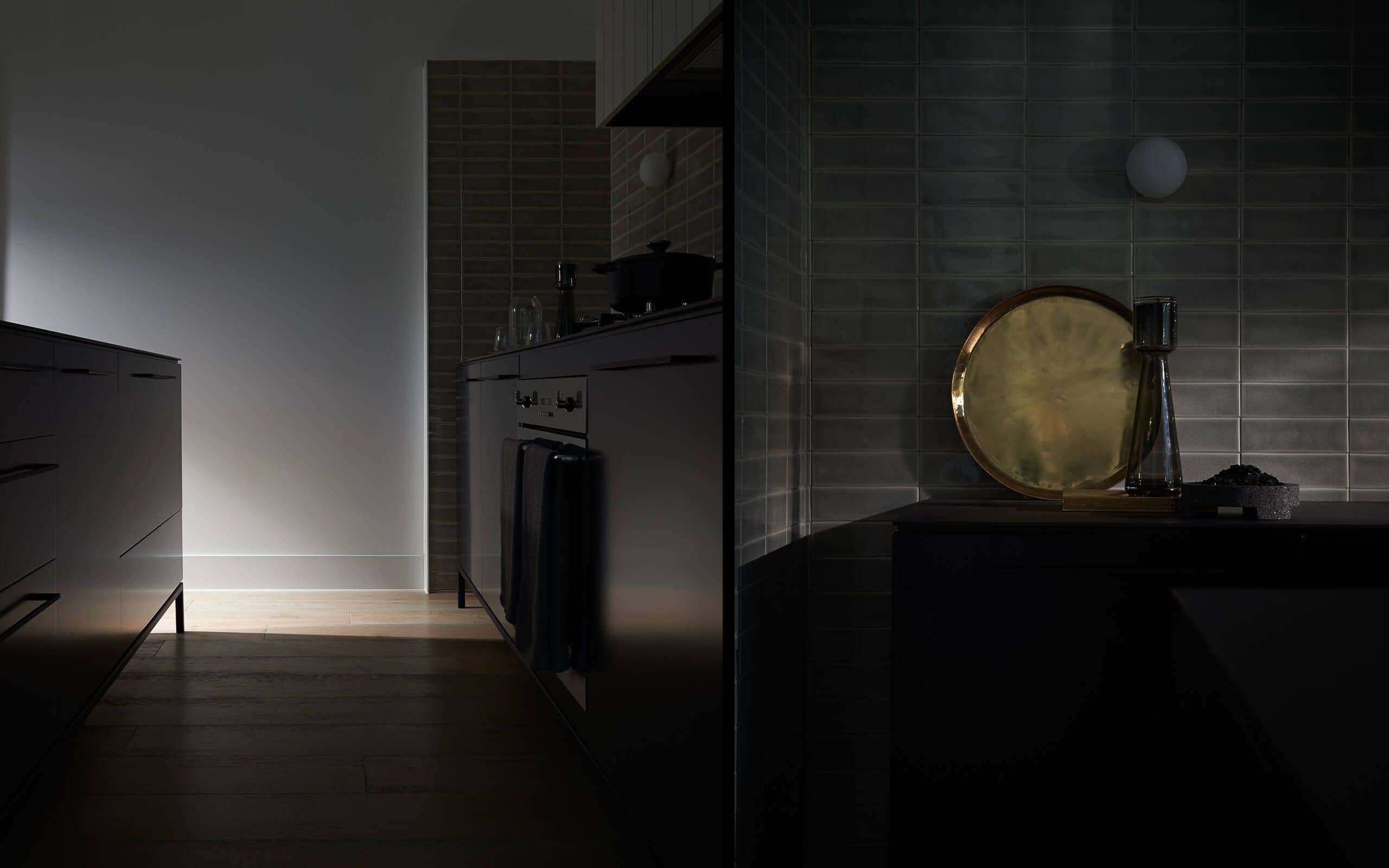 Split photo in dark tones, kitchen cabinets and a metal detail on the bench