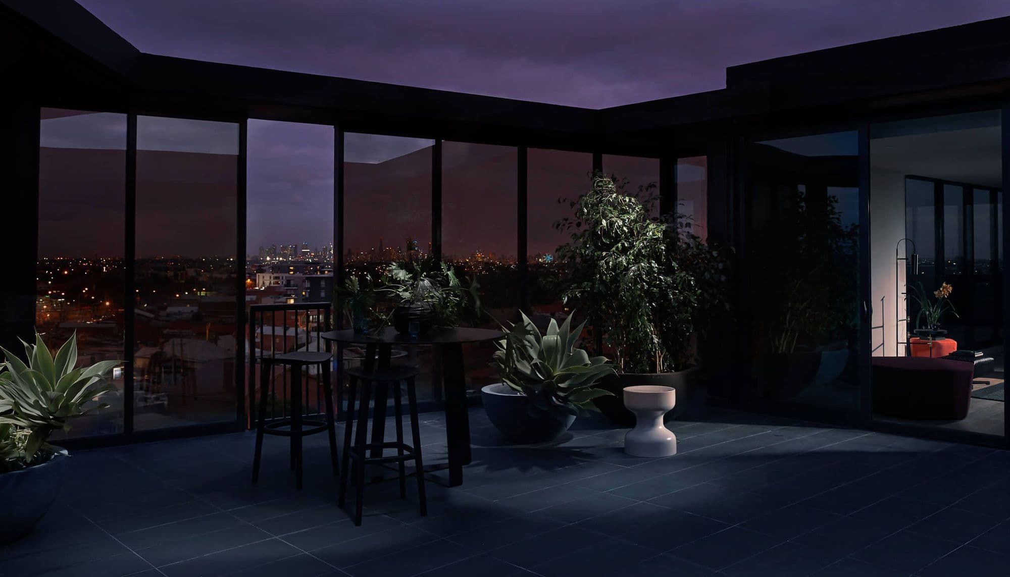 Wide photo o the courtyard in dark tones, with accent lights and plant leaves