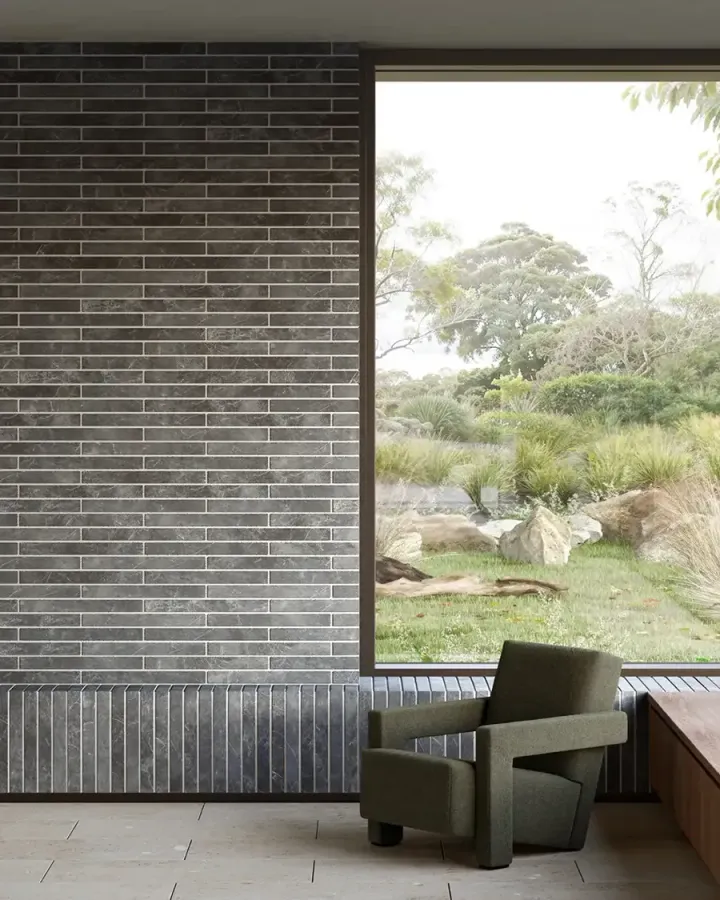 A dark late-century style brick facade in a sitting space, with a semi-natural garden outside
